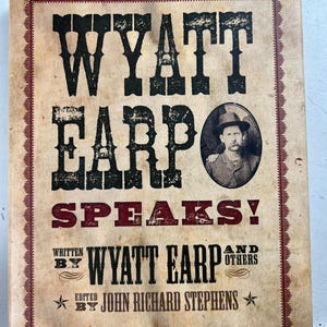 Peut inclure: Une couverture de livre de style vintage avec le titre "WYATT EARP SPEAKS!" en lettres noires et rouges audacieuses et usées. Un portrait d'un homme portant un chapeau est présenté. La couverture comprend également le texte "WRITTEN BY WYATT EARP AND OTHERS" et "EDITED BY JOHN RICHARD STEPHENS."