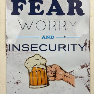 Op de afbeelding: Een verweerd metalen bord met de tekst "HOW TO STOP FEAR WORRY AND INSECURITY" in blauw en zwart. Een cartoon bierpul wordt door een hand vastgehouden, met het woord "BEER" eronder.