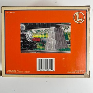 May include: A rectangular cardboard box with an orange background featuring a graphic illustration of a black steam locomotive train passing a stone bridge. The box includes the Lionel logo, the text 71-2744-200, a barcode, and 1996 Lionel LLC.