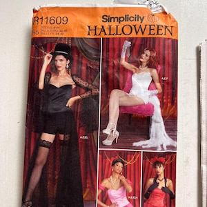 May include: Simplicity Halloween costume pattern. The orange and white package features images of women in various costumes, including a black outfit with a top hat, a white corset, and a pink outfit. The pattern size is U.S. 6-14.