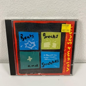 May include: A CD case with a colorful cover featuring the words "Beats," "Breaks," "and "Scratches." The cover has a black background with four squares in blue, green, and red. The CD is in a clear plastic case.