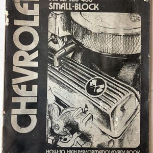 May include: A black and white Chevrolet Small-Block engine book cover. The cover features an illustration of an engine with the text "CHEVROLET" in large white letters. The book's title is "HOW-TO HIGH PERFORMANCE ENGINE BOOK".