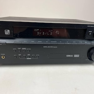 Pode incluir: Receptor multicanal de áudio e vídeo Pioneer preto VSC-816. O receptor possui um visor digital mostrando "DVD/LD -51". Possui vários botões e botões para várias funções. O componente superior tem o logotipo Pioneer.