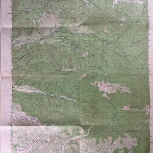 May include: A folded topographic map of the San Gorgonio Mountain Quadrangle in California. The map features green and brown shaded relief, contour lines, and grid lines. Text includes "United States Department of the Interior Geological Survey".