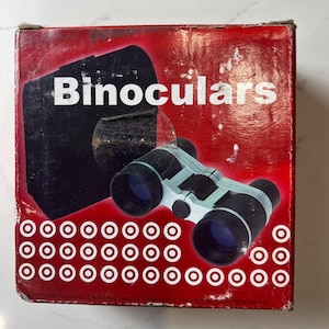 May include: A red box with the word "Binoculars" in white text. The box features a black and white illustration of binoculars. The box has a series of white circles with red centers.