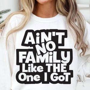 May include: White sweatshirt with the text "Ain't No Family Like The One I Got" in a bold, black, block-letter design. The sweatshirt is a casual, comfortable style, perfect for family gatherings or everyday wear.
