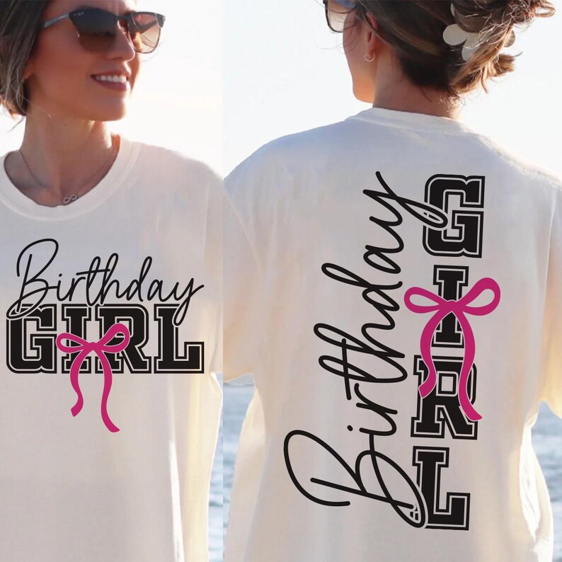 May include: Cream-colored t-shirt with the text "Birthday GIRL" in black script and block letters, accented with a pink bow. The back of the shirt repeats the text vertically. A casual, festive garment.