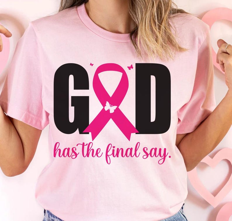 Puede incluir: Camiseta rosa claro con la palabra "GOD" en negro, una cinta rosa y la frase "has the final say" en cursiva. La cinta tiene una mariposa en el centro. Peque&ntilde;as mariposas a ambos lados de la cinta.
