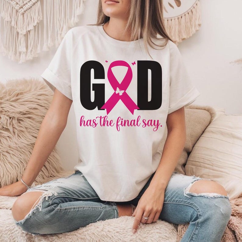 Puede incluir: Camiseta blanca con el texto "GOD has the final say". La palabra "GOD" es negra, con un dise&ntilde;o de cinta rosa en lugar de la "O". La frase "has the final say" est&aacute; en escritura rosa.