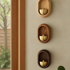 Peut inclure: Trois éléments décoratifs muraux en bois de forme ovale. Chacun contient un bol de couleur laiton. Les couleurs du bois varient du brun clair au foncé, créant une esthétique naturelle et minimaliste.