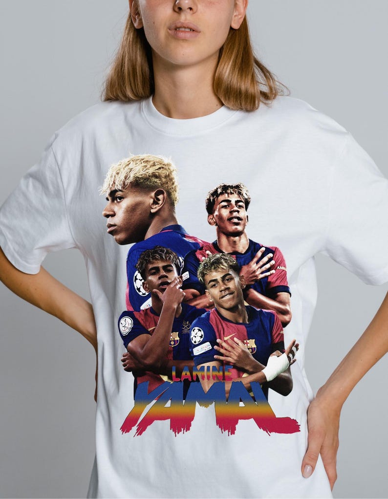 May include: White t-shirt with a graphic of a footballer in a blue and red kit. The design includes the name "Lamine Yamal" in colourful text. The graphic features multiple images of the player in action.