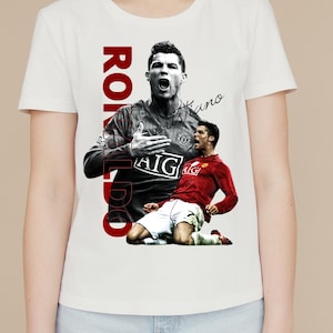Pu&ograve; includere: T-shirt bianca con grafica di calciatore in rosso e nero. Il nome "Ronaldo" &egrave; stampato verticalmente in rosso, con "Cristiano" in corsivo. La maglietta &egrave; a girocollo.