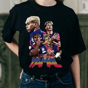 May include: Black t-shirt with a graphic of a soccer player in multiple poses. The design includes the name "LAMINE YAMAL" in a colourful, stylised font, with a Barcelona team logo.