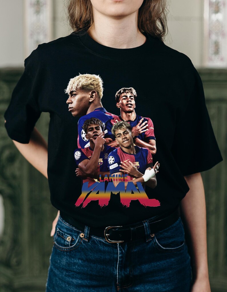 May include: Black t-shirt with a graphic of a soccer player in multiple poses. The design includes the name "LAMINE YAMAL" in a colourful, stylised font, with a Barcelona team logo.