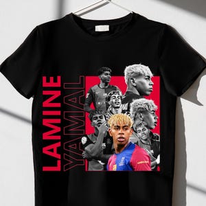 May include: Black t-shirt with a red rectangle containing multiple images of Lamine Yamal. The name "LAMINE YAMAL" is printed vertically in red on the left. The shirt is displayed on a white hanger, ready for wear.