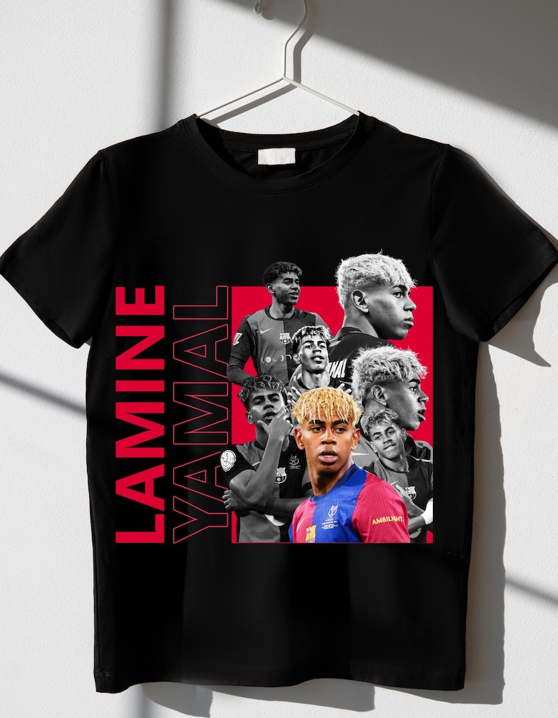 May include: Black t-shirt with a red rectangle containing multiple images of Lamine Yamal. The name "LAMINE YAMAL" is printed vertically in red on the left. The shirt is displayed on a white hanger, ready for wear.