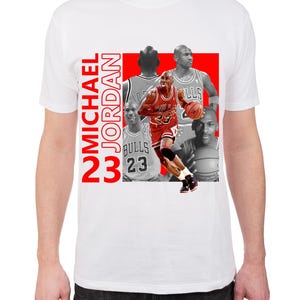 May include: White t-shirt featuring a graphic of Michael Jordan in action, with the number 23 and the name "MICHAEL JORDAN" in red. The design includes multiple images of Jordan.