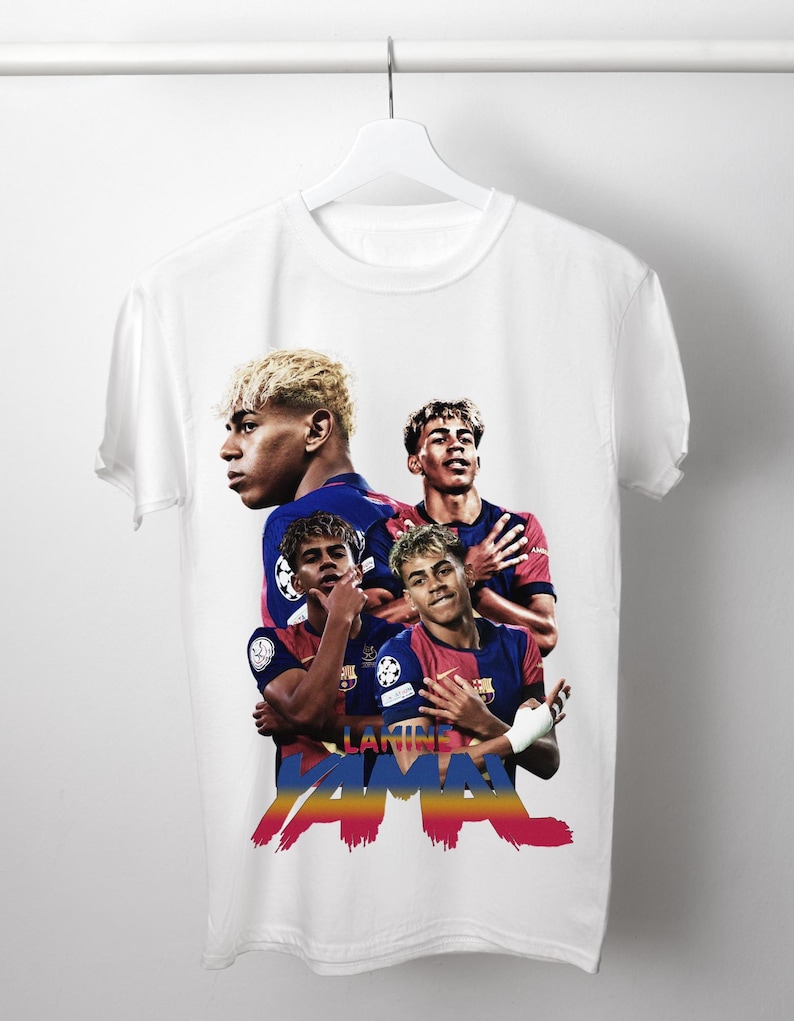 May include: White t-shirt with a design featuring a soccer player in a blue and red uniform. The design includes the player's image and the name "LAMINE YAMAL" in a colourful, stylised font.