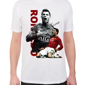 Pu&ograve; includere: T-shirt bianco con grafica di un calciatore in maglia rossa, con la scritta "RONALDO" in rosso in verticale. La maglietta include anche una firma e i loghi "AIG" e "Nike".