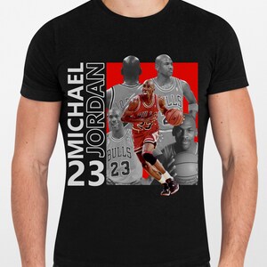 May include: Black t-shirt featuring a collage of Michael Jordan in action. The design includes images of Jordan in his Bulls uniform, with the text "MICHAEL JORDAN 23" in white. The background is a red rectangle.