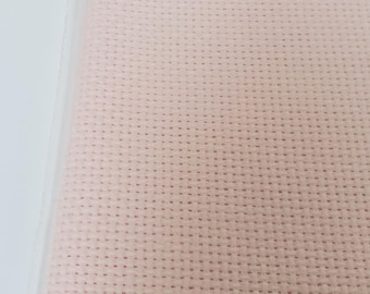 May include: A sheet of pale pink cross-stitch fabric, packaged in a clear plastic bag. The fabric has a grid-like pattern of small, evenly spaced holes, ideal for needlework projects. The bag is sealed at the top.
