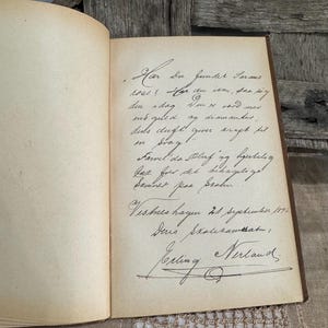 May include: An open antique book with handwritten text in black ink on aged, cream-colored pages. The text includes cursive script, a signature, and the date September 21, 1896. The book's binding is visible.