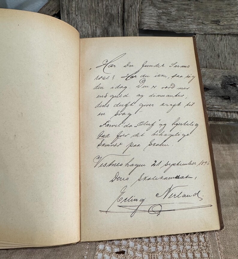 May include: An open antique book with handwritten text in black ink on aged, cream-colored pages. The text includes cursive script, a signature, and the date September 21, 1896. The book's binding is visible.