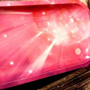 May include: A rectangular tray with rounded corners, featuring a pink and purple disco ball design. White star-like accents and light rays emanate from the center. The tray is likely made of a durable material.