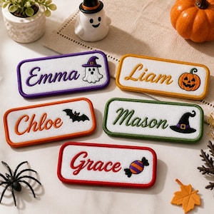 May include: Five rectangular embroidered name patches with white fabric centers and colored borders. The patches feature the names Emma, Liam, Chloe, Mason, and Grace, each accompanied by a Halloween-themed icon including a ghost, pumpkin, bat, witch hat, and candy.