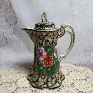 May include: A set of three ceramic mugs with a speckled, matte finish. The mugs are in shades of cream, light brown, and dark brown. Each mug has a simple, minimalist design and a rounded handle.