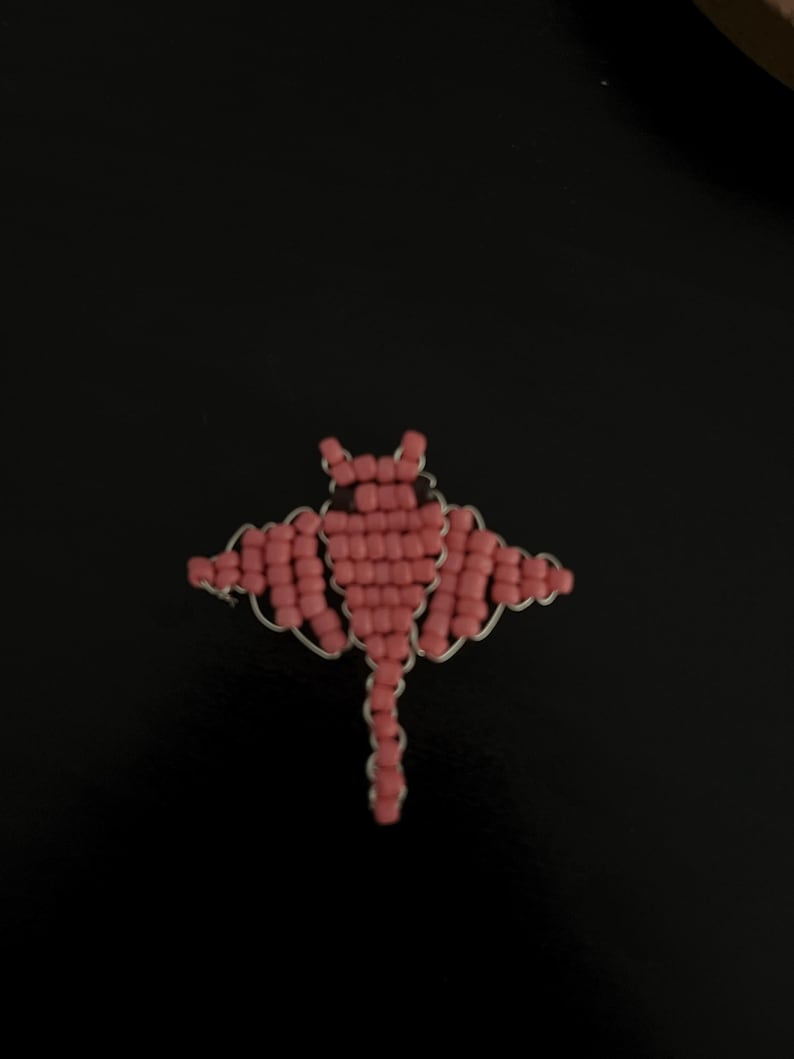 Pu&ograve; includere: Spilla a forma di pipistrello in perline rosa con dettagli in filo d'argento. Il pipistrello ha le ali spiegate e un corpo dettagliato, perfetto per aggiungere un tocco unico a qualsiasi outfit. Un accessorio fatto a mano.