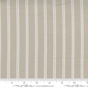 May include: Tan fabric with vertical white stripes. The stripes have a textured, woven appearance. The fabric is a neutral color, suitable for various sewing and crafting projects. The image includes a ruler along the bottom edge.