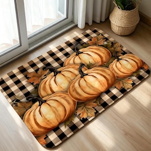 May include: A rectangular floor mat featuring a black and white buffalo check pattern decorated with a cluster of orange pumpkins and brown autumn leaves. The design is centered on the mat, showcasing multiple pumpkins with dark stems.