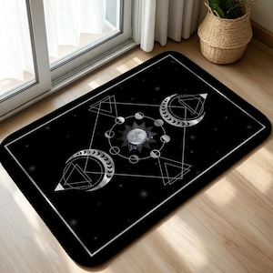 May include: A rectangular black floor mat featuring a white and silver celestial design. The graphic includes a central full moon surrounded by a lunar phase cycle, two crescent moons, and geometric triangle patterns on a starry background.