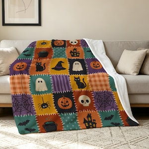 Könnte beinhalten: Eine Plüschdecke mit einem Patchwork-Design aus Halloween-Motiven, darunter orangefarbene Kürbisse, schwarze Katzen, weiße Geister, Totenköpfe, Hexenhüte, Kessel, Spinnen, Fledermäuse und Spukhäuser in Orange, Lila, Blaugrün und Schwarz.
