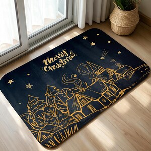 以下が含まれることがあります： 家、木、星が描かれた冬の村の金色の線画が特徴の、長方形の濃い青色のフロアマット。マットのデザインの上部には、金色の筆記体でMerry Christmasという文字がプリントされています。