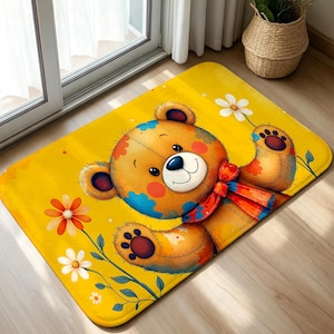 Può includere: Un tappetino rettangolare con uno sfondo giallo brillante e l'illustrazione di un orsacchiotto. L'orso ha il pelo marrone con macchie blu, un papillon rosso ed è circondato da fiori bianchi e arancioni con steli e foglie verdi.