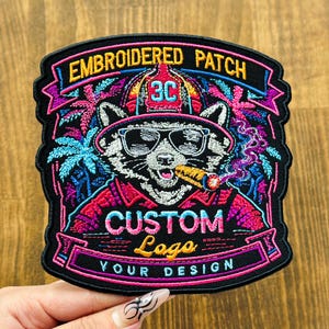 May include: Embroidered patch featuring a raccoon wearing sunglasses and smoking a cigar. The patch has the text "Embroidered Patch", "Custom Logo", and "Your Design". The design includes palm trees and vibrant colors.