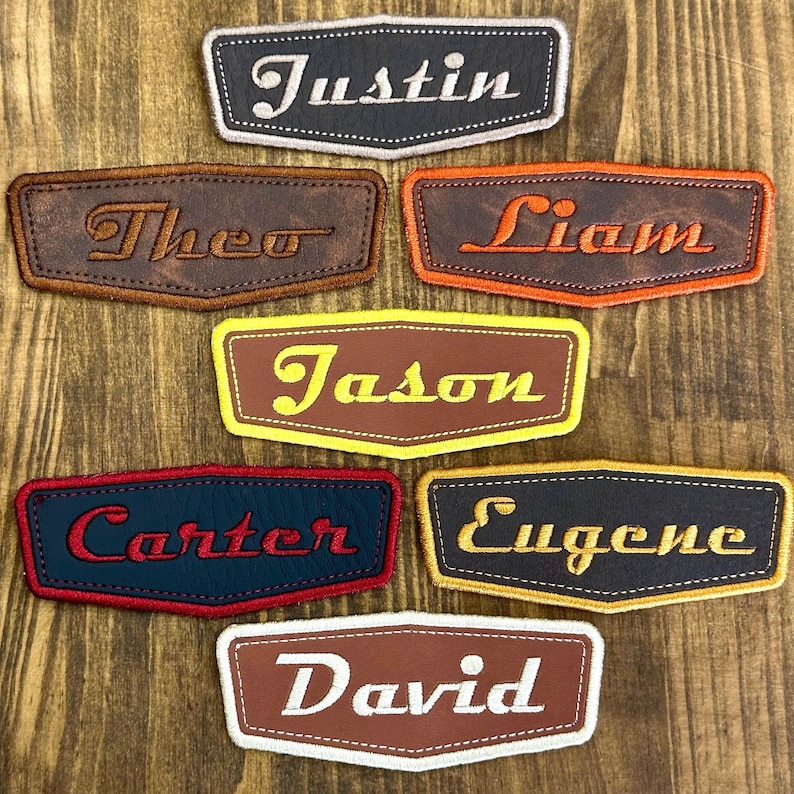 May include: A collection of personalized name patches in various colors and fonts. Each patch features a different name, including "Justin," "Theo," "Liam," "Jason," "Carter," "Eugene," and "David." The patches are rectangular with rounded edges.