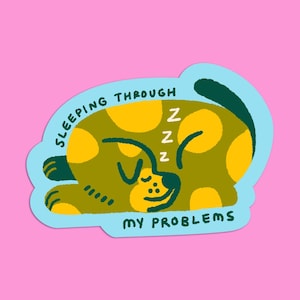 May include: A sticker featuring a cartoon dog sleeping. The dog is olive green with yellow spots and the text "SLEEPING THROUGH MY PROBLEMS" in a blue border. The dog has the letter "Z" repeated three times above its head.
