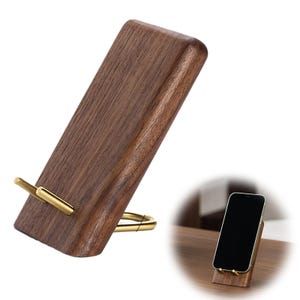 Può includere: Un supporto per telefono in legno marrone scuro con un supporto in metallo color ottone. Il supporto è angolato per una visione ottimale e ha un design minimalista. Il supporto è progettato per contenere uno smartphone.