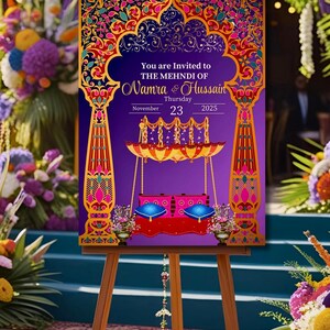 Könnte beinhalten: Ein hölzernes Staffelei zeigt eine farbenfrohe Einladung zur Mehndi von Namra & Hussain. Das Design zeigt verzierte Torbögen, eine Schaukel und den Text „You are Invited“. Die Farbpalette umfasst Lila, Gold, Rosa und Blau. Datum: 23. November 2025.