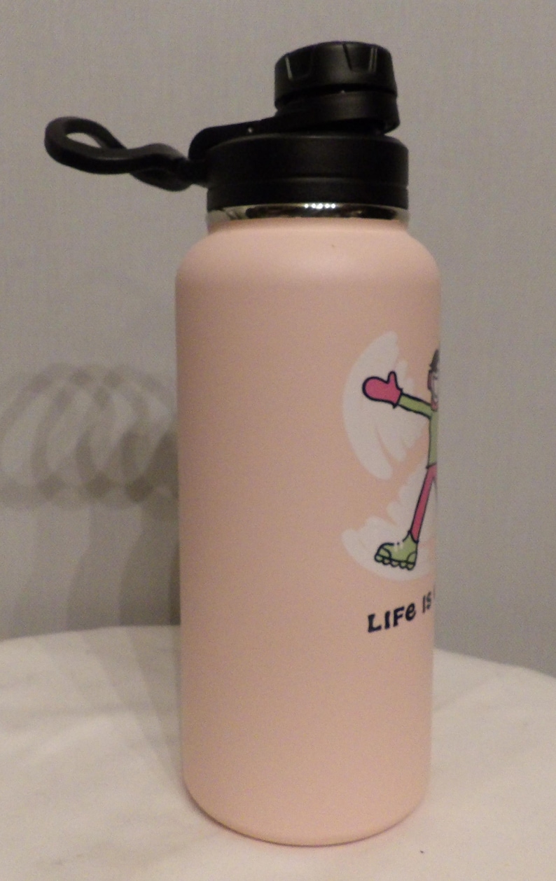 K&ouml;nnte beinhalten: Eine hellrosa isolierte Wasserflasche mit schwarzem Deckel und Griff. Die Flasche zeigt eine Cartoon-Grafik einer Person, die einen Schneeengel macht, mit den Worten "Life is" unter der Grafik.