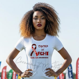 May include: White t-shirt featuring a red and black ribbon graphic and the words "TOGETHER WE FIGHT" and "Sickle Cell AWARENESS". The shirt has short sleeves.