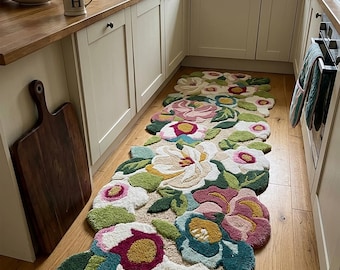 May include: A long, tufted runner rug featuring a vibrant, multi-colored floral pattern with large, organic-shaped blooms in shades of pink, white, yellow, teal, and green. The rug has a textured, high-pile surface and irregular, scalloped edges.