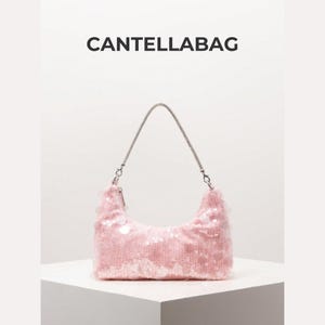 May include: A pink sequined shoulder bag with a silver chain strap. The bag has a curved shape and is embellished with numerous sequins. The text "CANTELLABAG" is displayed above the bag.