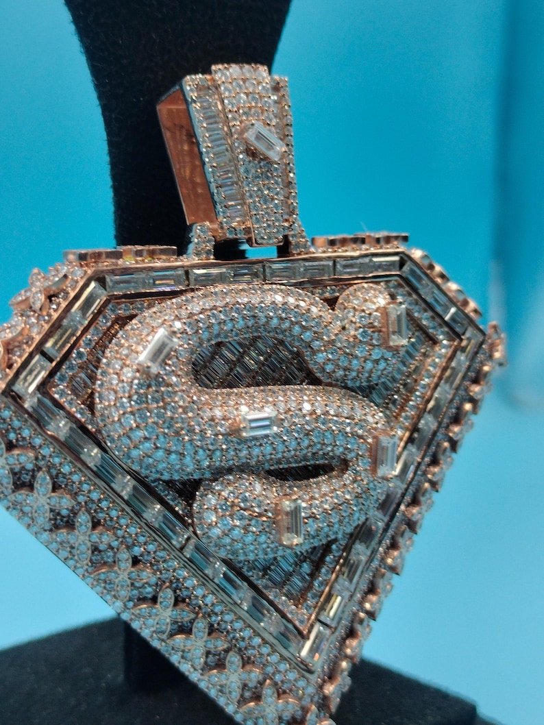 May include: A diamond-encrusted pendant with a rose gold finish. The pendant features a diamond-studded snake design within a diamond-shaped frame. The frame is also adorned with diamonds, creating a luxurious and eye-catching piece of jewelry.