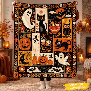 Op de afbeelding: Een rechthoekige plaid met een raster van Halloween-illustraties, waaronder geesten, zwarte katten, pompoenen, vleermuizen, een uil en een kom met snoep. Het ontwerp gebruikt een kleurenpalet van zwart, oranje, crème en wit met bloemenranden.