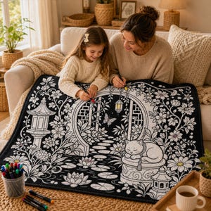 May include: A rectangular fabric mat featuring a black and white line art illustration of a garden scene with a sleeping cat, a stone lantern, a circular gate, a butterfly, and lotus flowers, designed for colouring with markers on a soft surface.