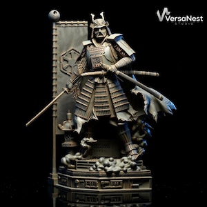 May include: A detailed statue of a samurai warrior in metallic armor, holding two katanas. The figure stands on a decorative base with a banner featuring a symbol. The statue has a dark, weathered appearance, with intricate detailing on the armor and weapons.